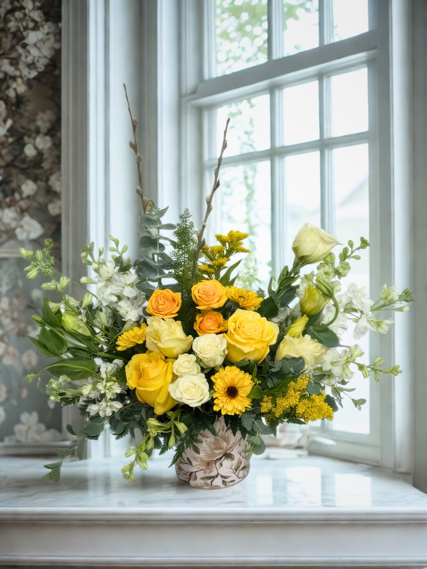 Yellow and white floral arrangement in a floral-print vase