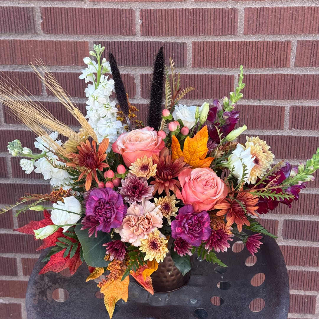 Autumn bouquet with pink roses, chrysanthemums, and white blooms in a dark vase