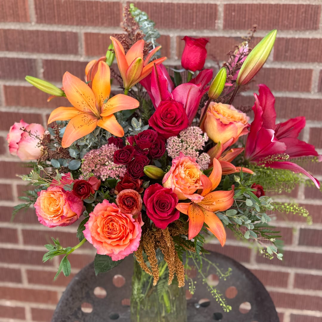 Bouquet of orange lilies and red roses in a glass vase