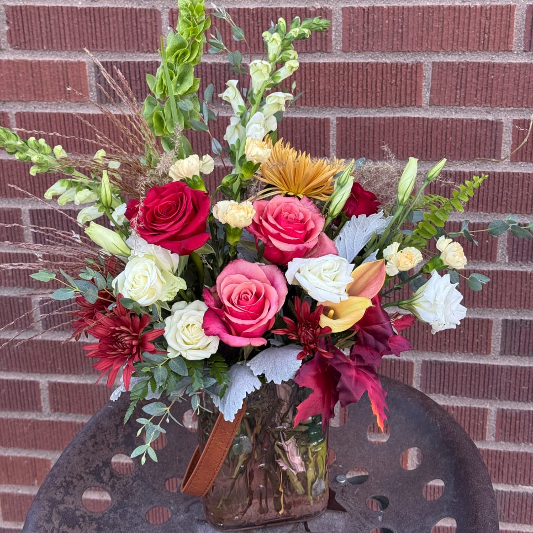 Mixed bouquet of roses, snapdragons, and calla lilies in a glass vase