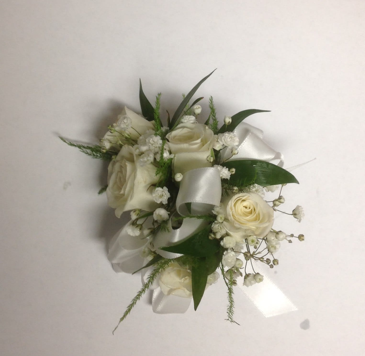 White rose corsage with satin ribbon and greenery