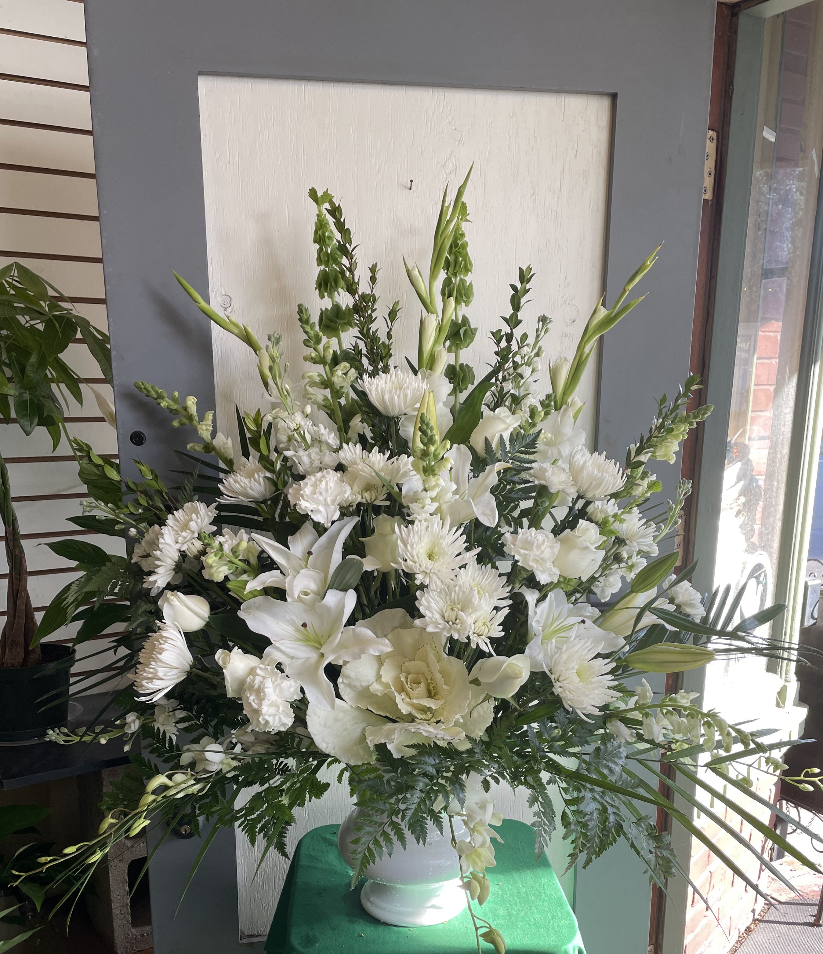 Large white floral arrangement in a white vase with lilies and chrysanthemums