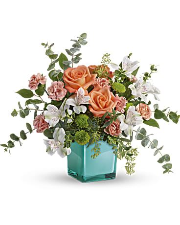Peach roses, pink carnations and white alstroemeria in a teal glass cube vase