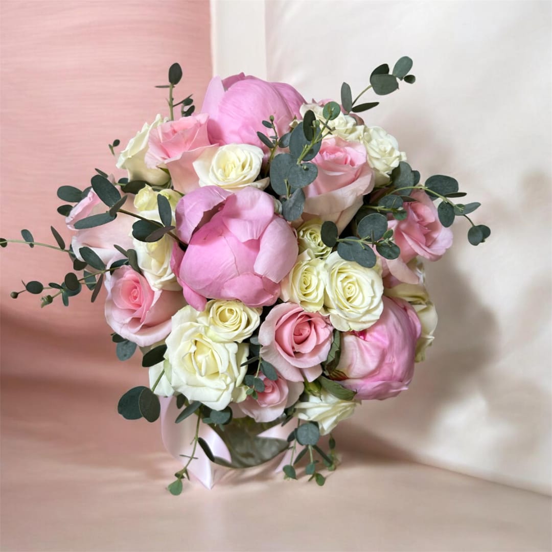 Pink and white rose bouquet with eucalyptus in a clear vase
