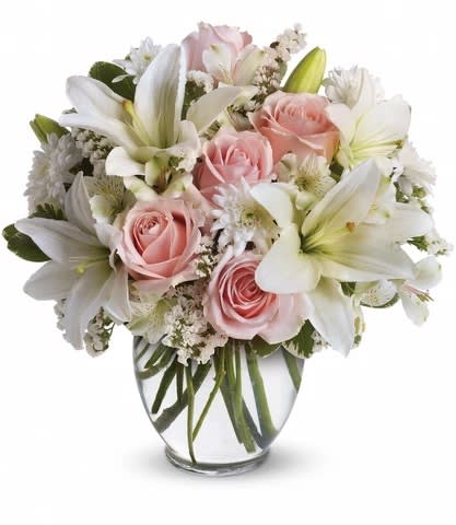 Pink roses and white lilies arranged in a clear glass vase