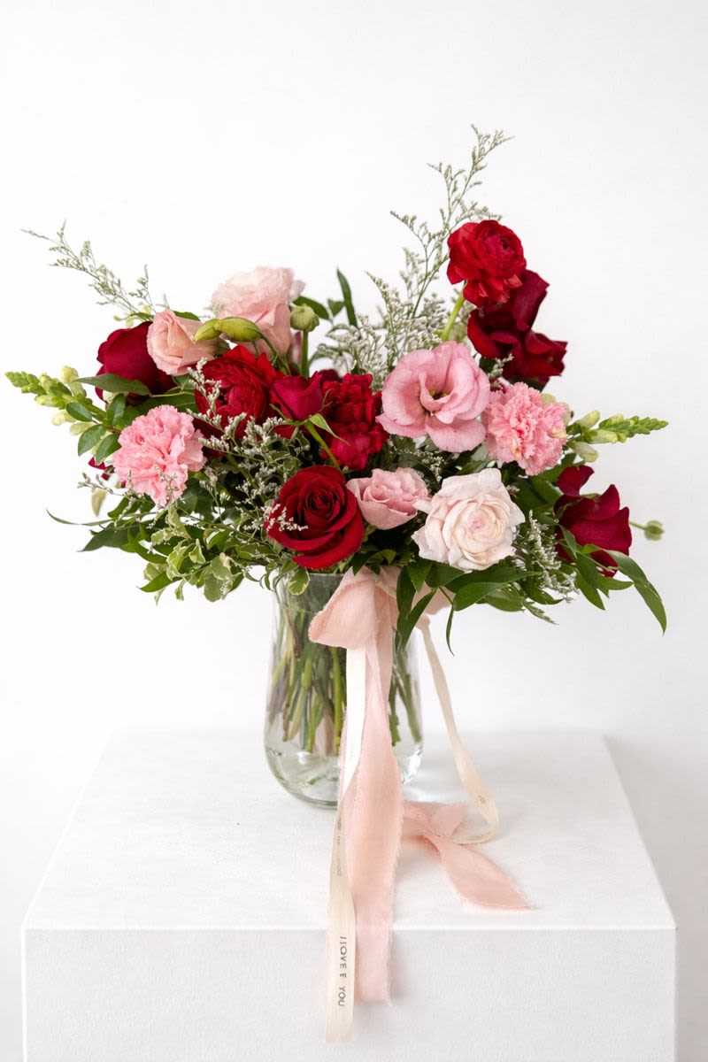 Bouquet of red and pink roses in a glass vase with a pink ribbon