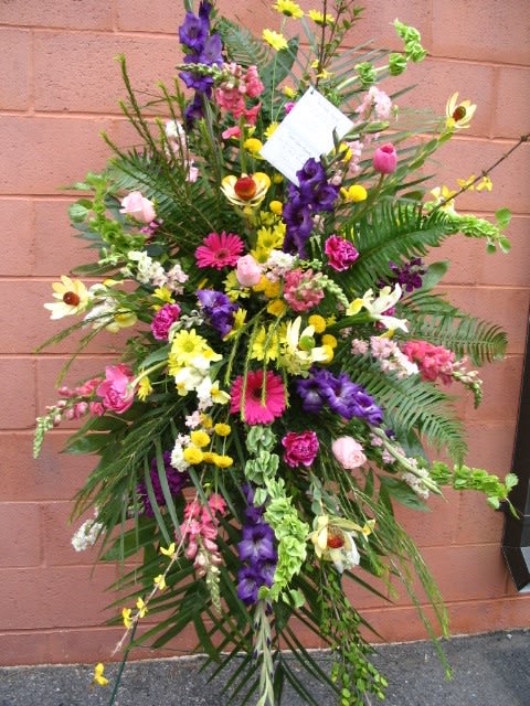 Tall standing floral spray with mixed bright flowers and greenery