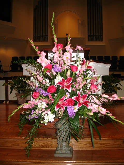 Large pink and white floral arrangement in a stone vase