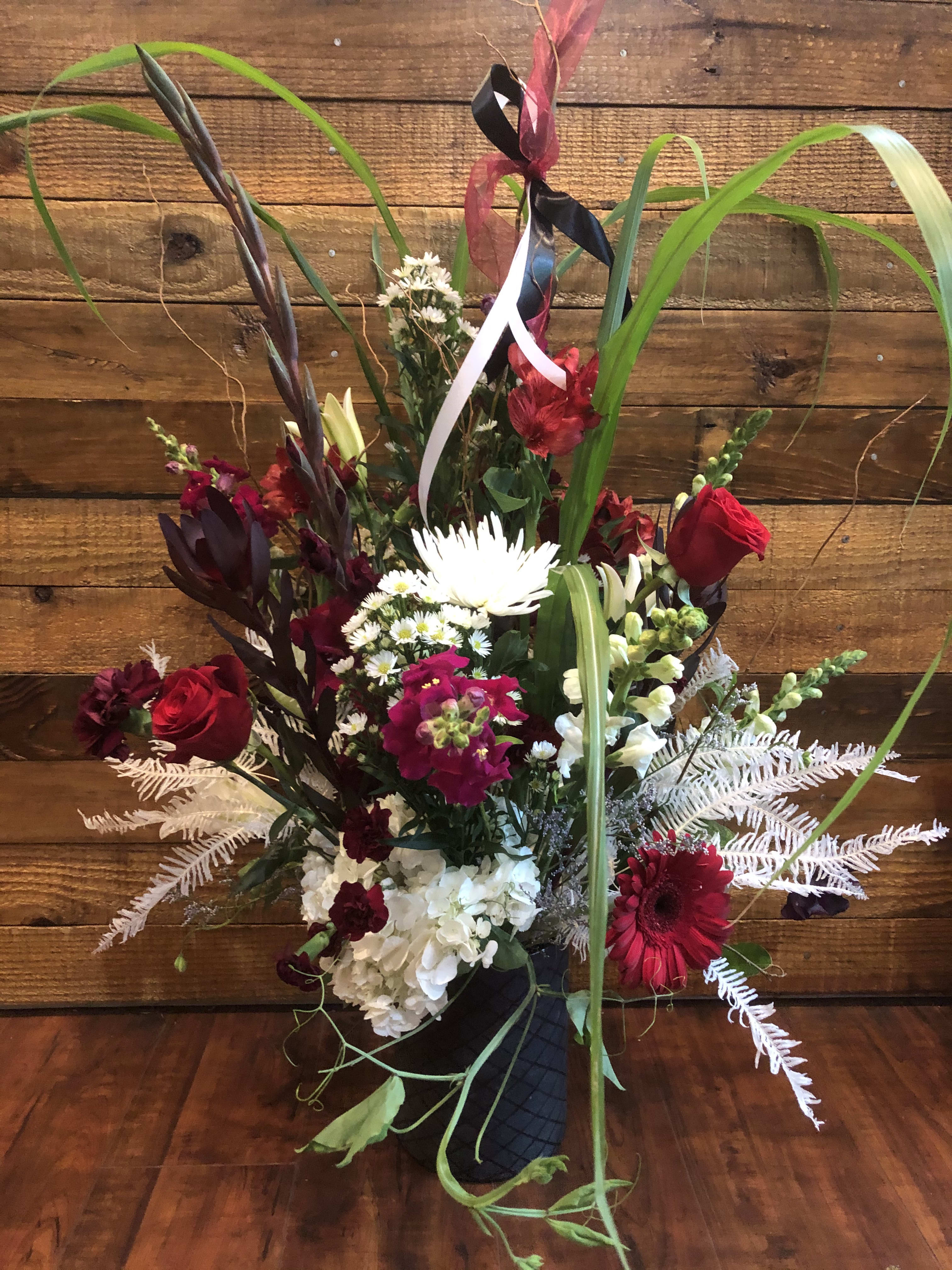 Tall mixed bouquet with red and white flowers in a black vase