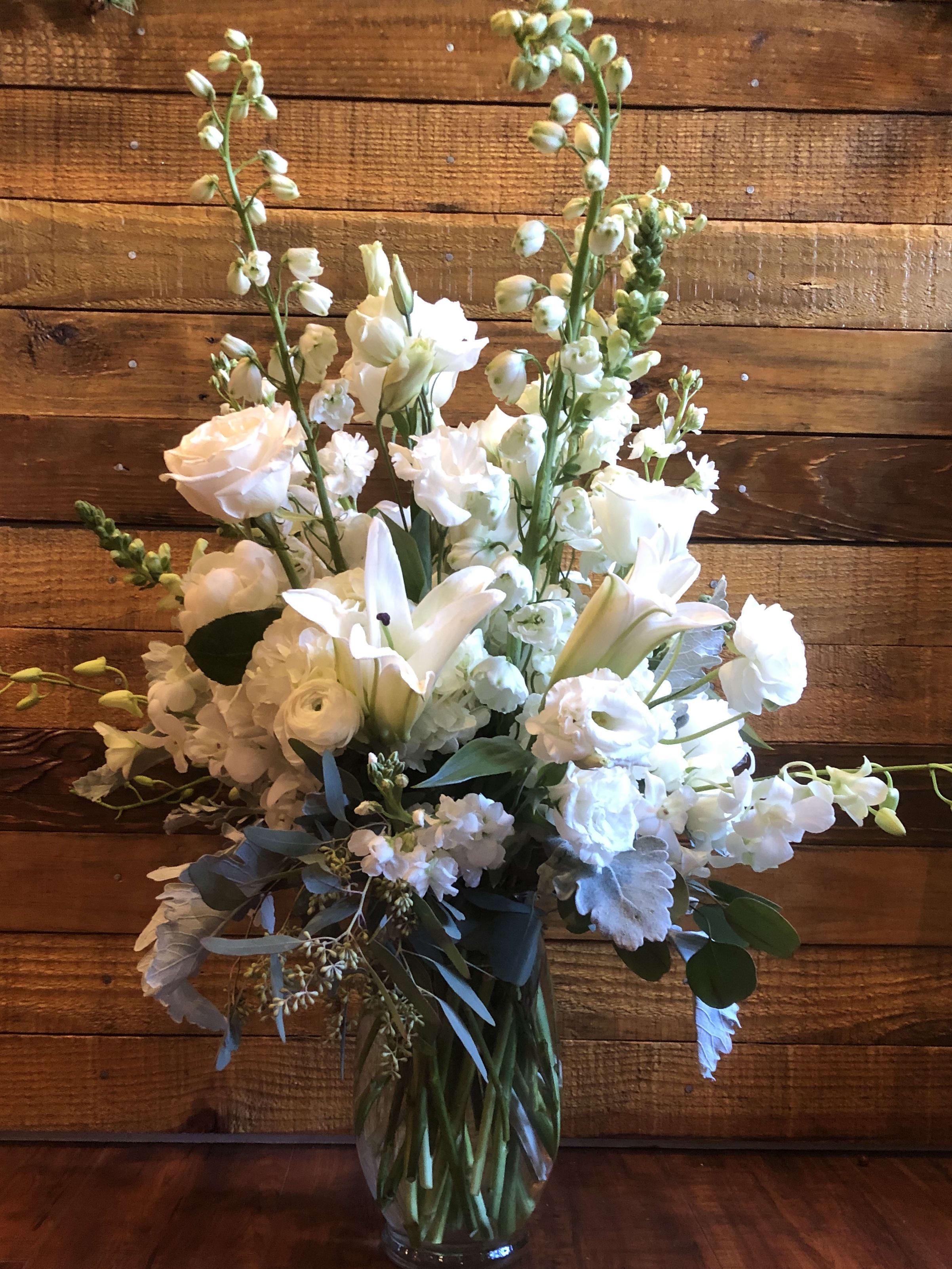 White floral arrangement in a clear glass vase with tall stems and mixed blooms