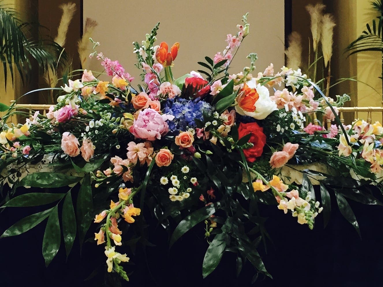 Large floral arrangement with pink, peach, white, and red blooms
