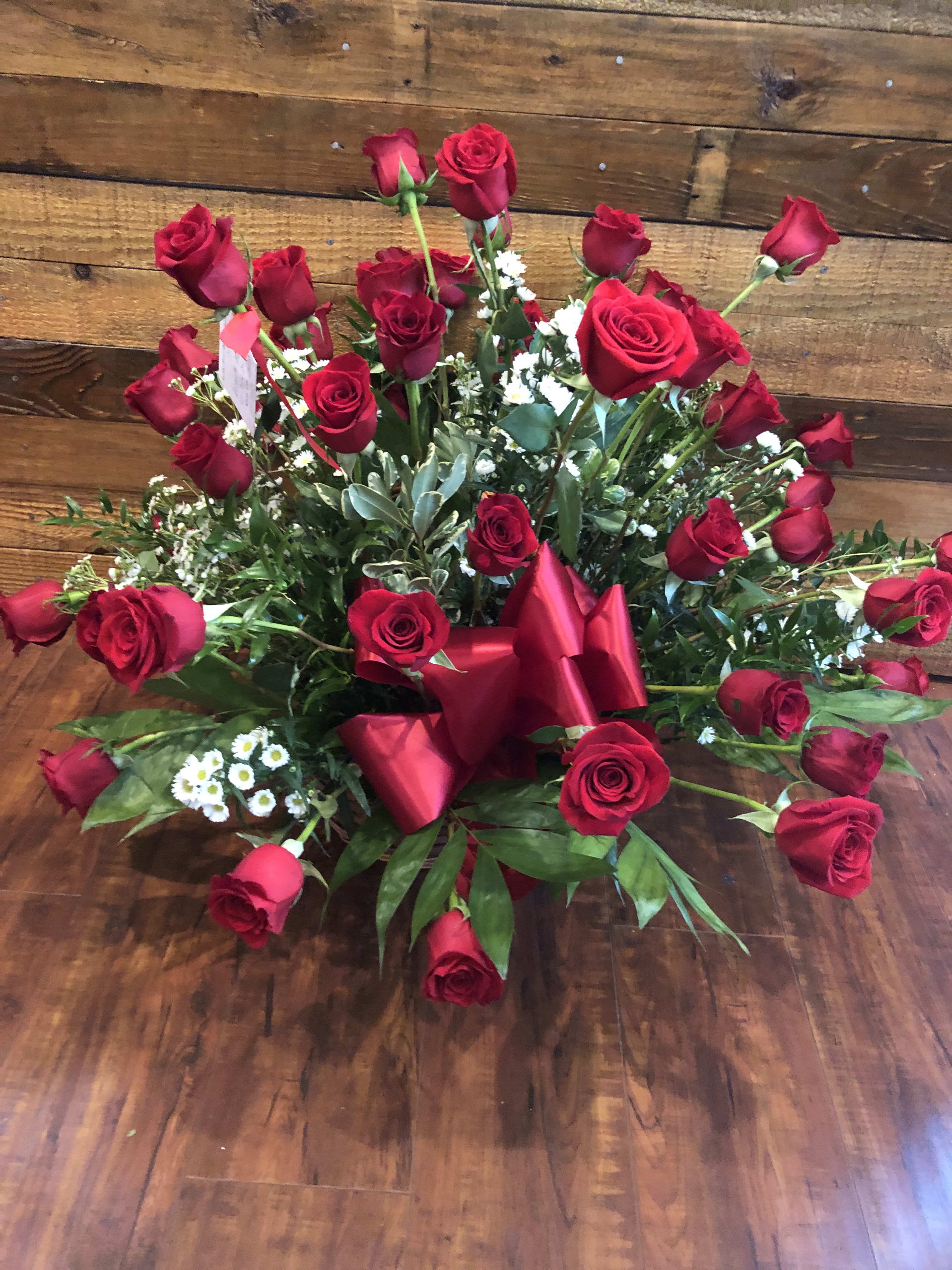 Large bouquet of red roses with greenery and a red ribbon