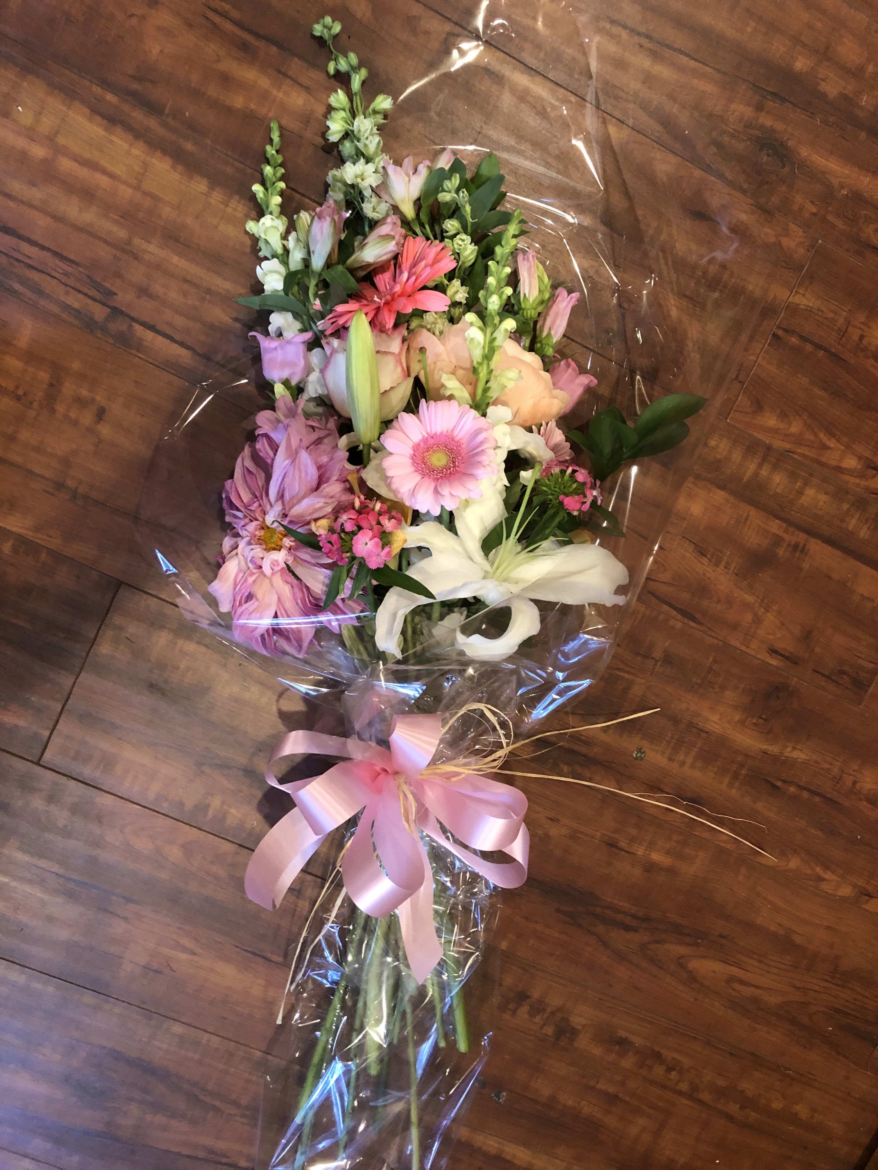 Mixed bouquet with pink, white, and peach flowers wrapped in clear plastic