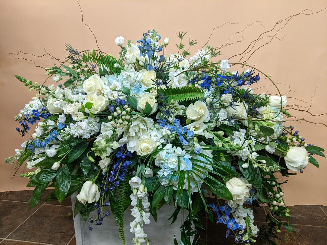 Large white and blue floral arrangement in a rectangular container
