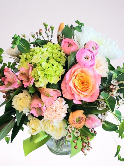 Mixed bouquet of pink, white, and green flowers in a glass vase