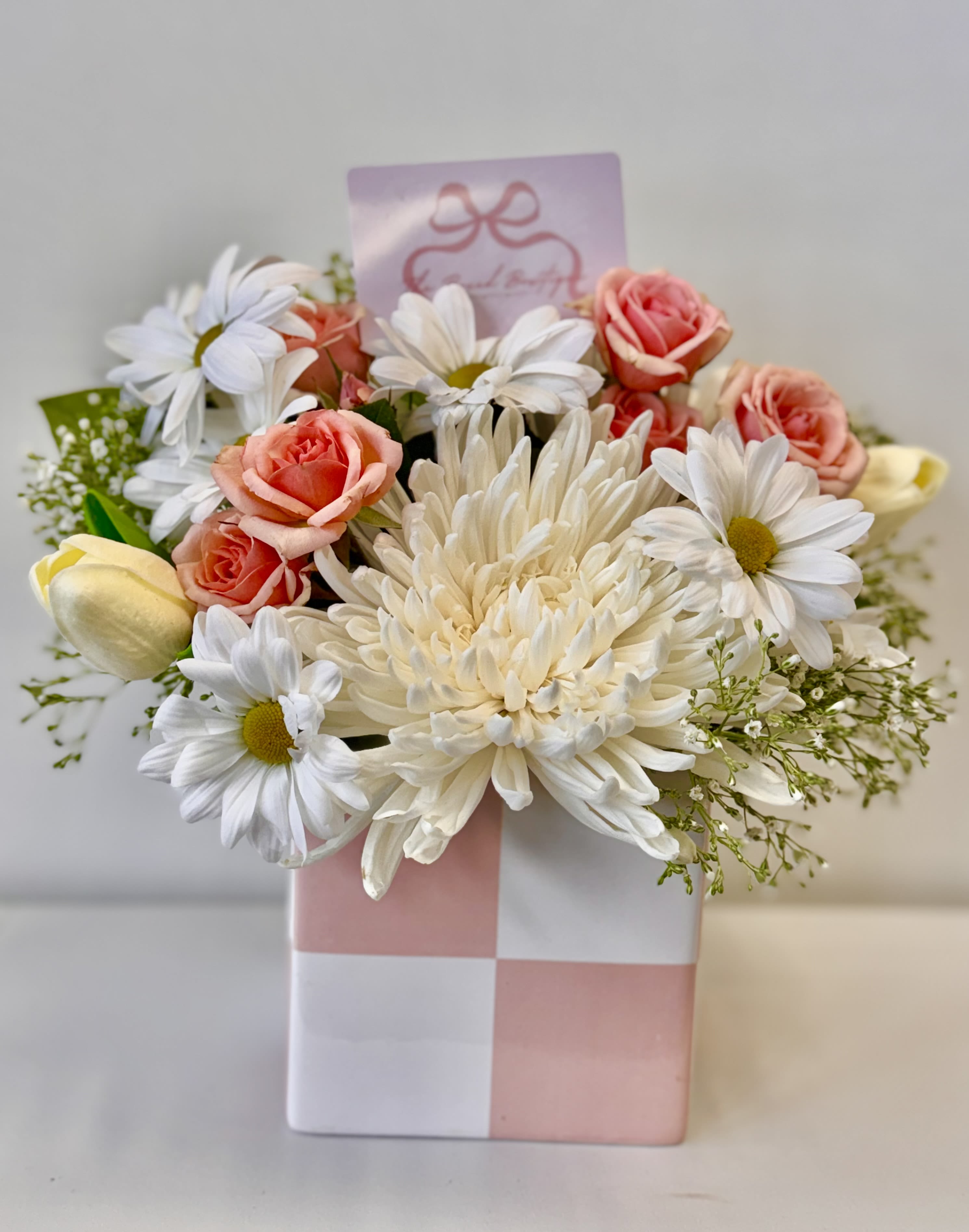 Pink and white flower arrangement in a checkered gift box