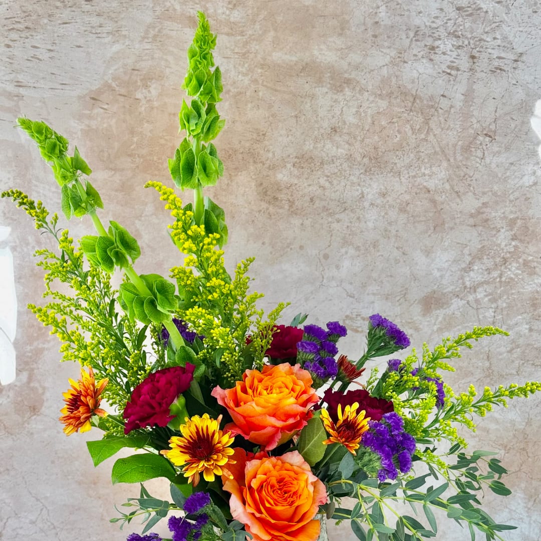 Orange roses with purple and yellow flowers in a mixed bouquet