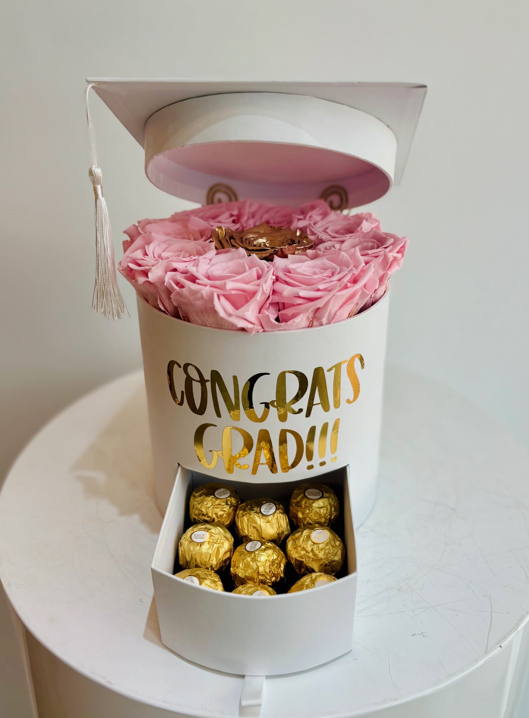 Pink roses in a white graduation gift box with chocolates