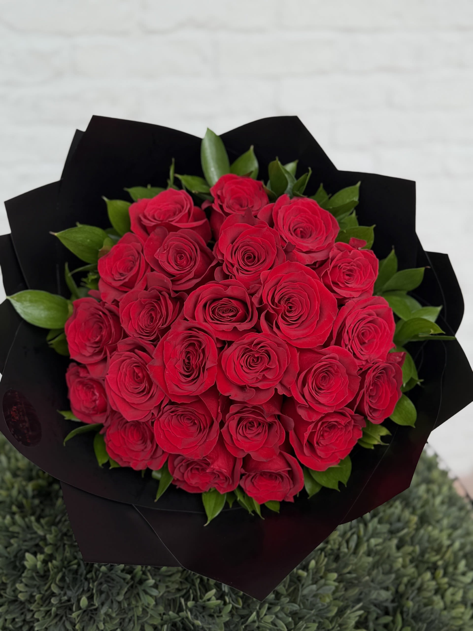 Round bouquet of red roses wrapped in black paper