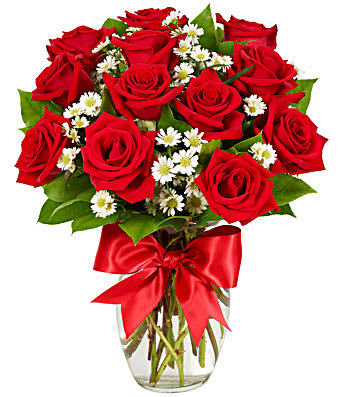 Arrangement of red roses and small white daisies in a clear glass vase with a red satin bow
