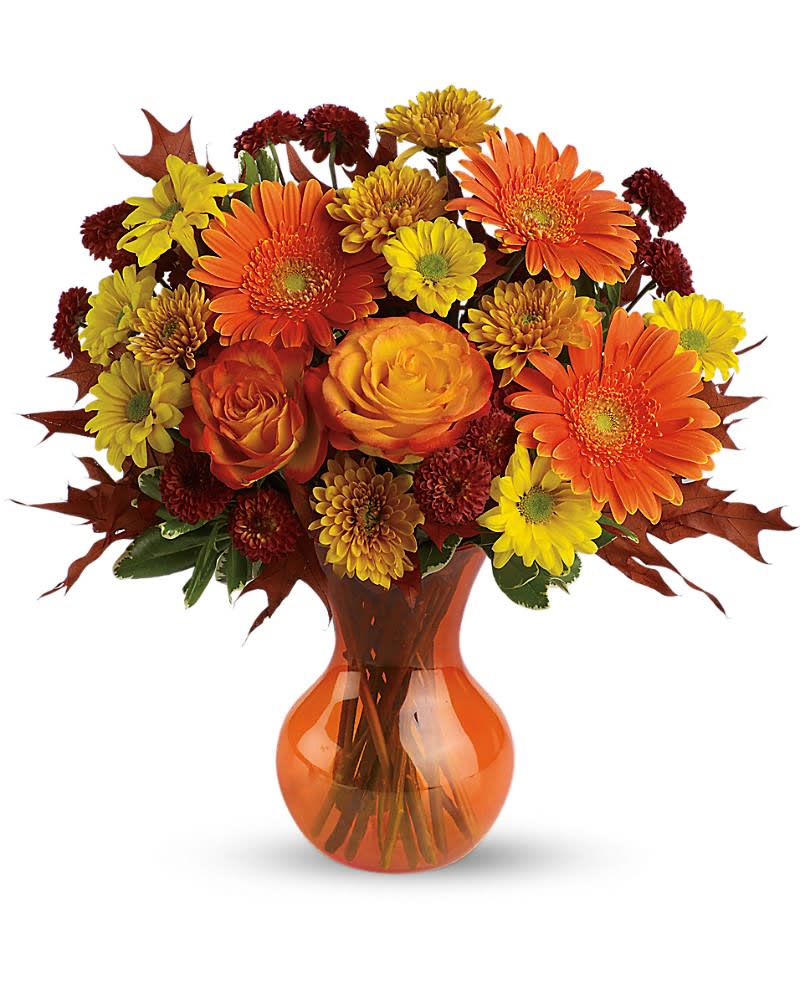 Arrangement of orange gerbera daisies, roses, and yellow mums in an orange glass vase
