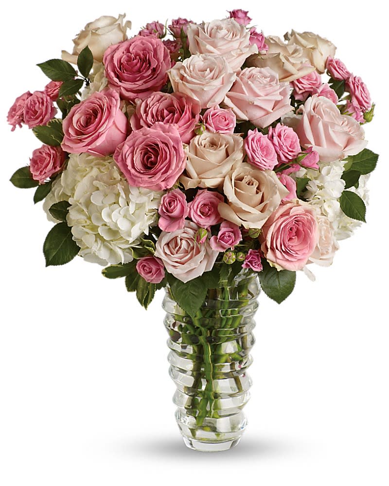 Tall clear glass vase with pink and ivory roses and white hydrangeas in a full rounded arrangement