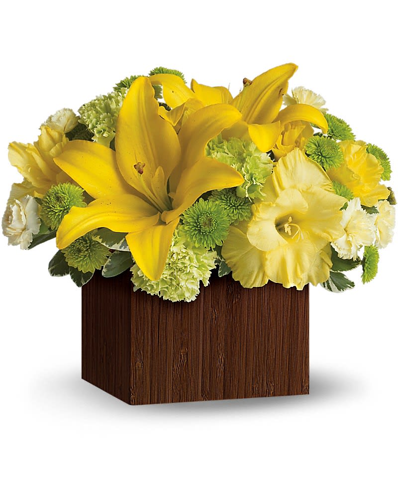 Low arrangement of yellow lilies and mixed yellow and green flowers in a brown wood cube.
