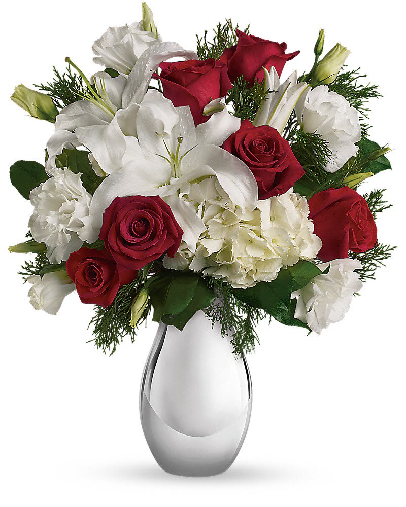 Arrangement of red roses, white lilies, and white flowers in a shiny silver vase