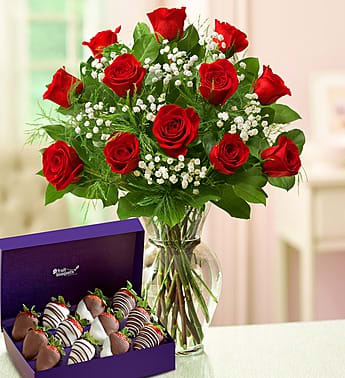 Red rose bouquet in a glass vase beside a purple box of chocolate-covered strawberries