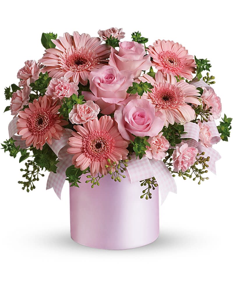 Pink arrangement of gerbera daisies, roses, and carnations in a light pink cylinder vase with ribbon