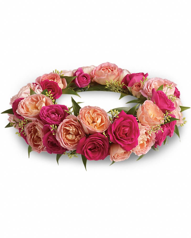 Low circular wreath of hot pink and peach roses arranged in a ring.