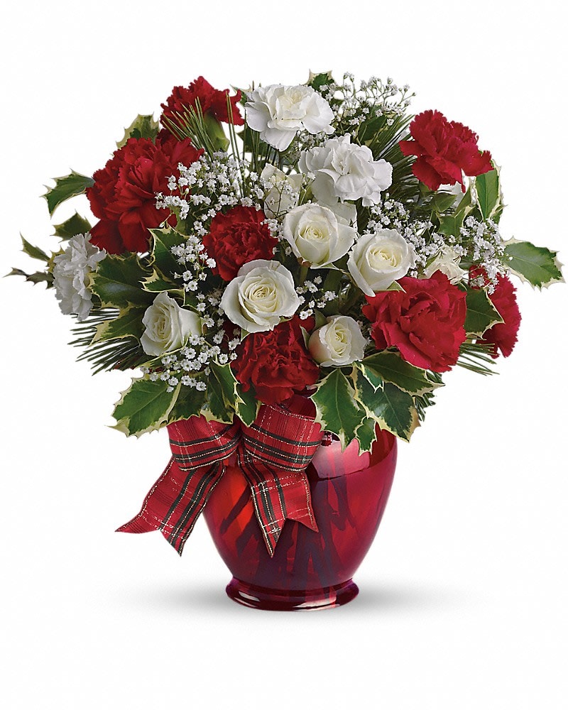 Round arrangement of red carnations and white roses in a red vase with a plaid ribbon bow