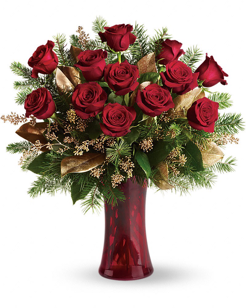 Arrangement of red roses with evergreen and gold accents in a tall red glass vase