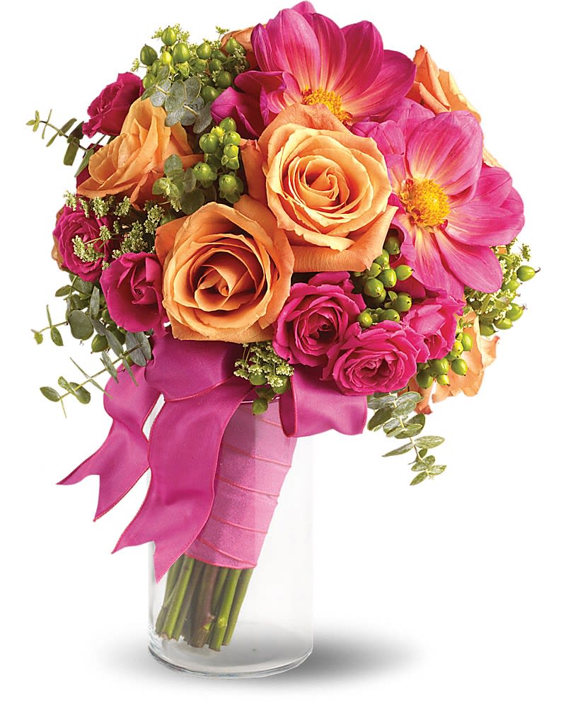 Hand-tied bouquet of orange roses and bright pink flowers wrapped in pink ribbon in a clear glass vase