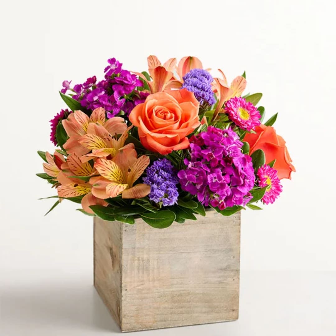 Mixed bouquet of orange, pink, and purple flowers in a wooden box