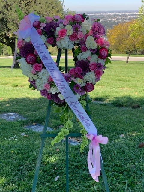 Heart-shaped floral wreath on an easel with a pink ribbon
