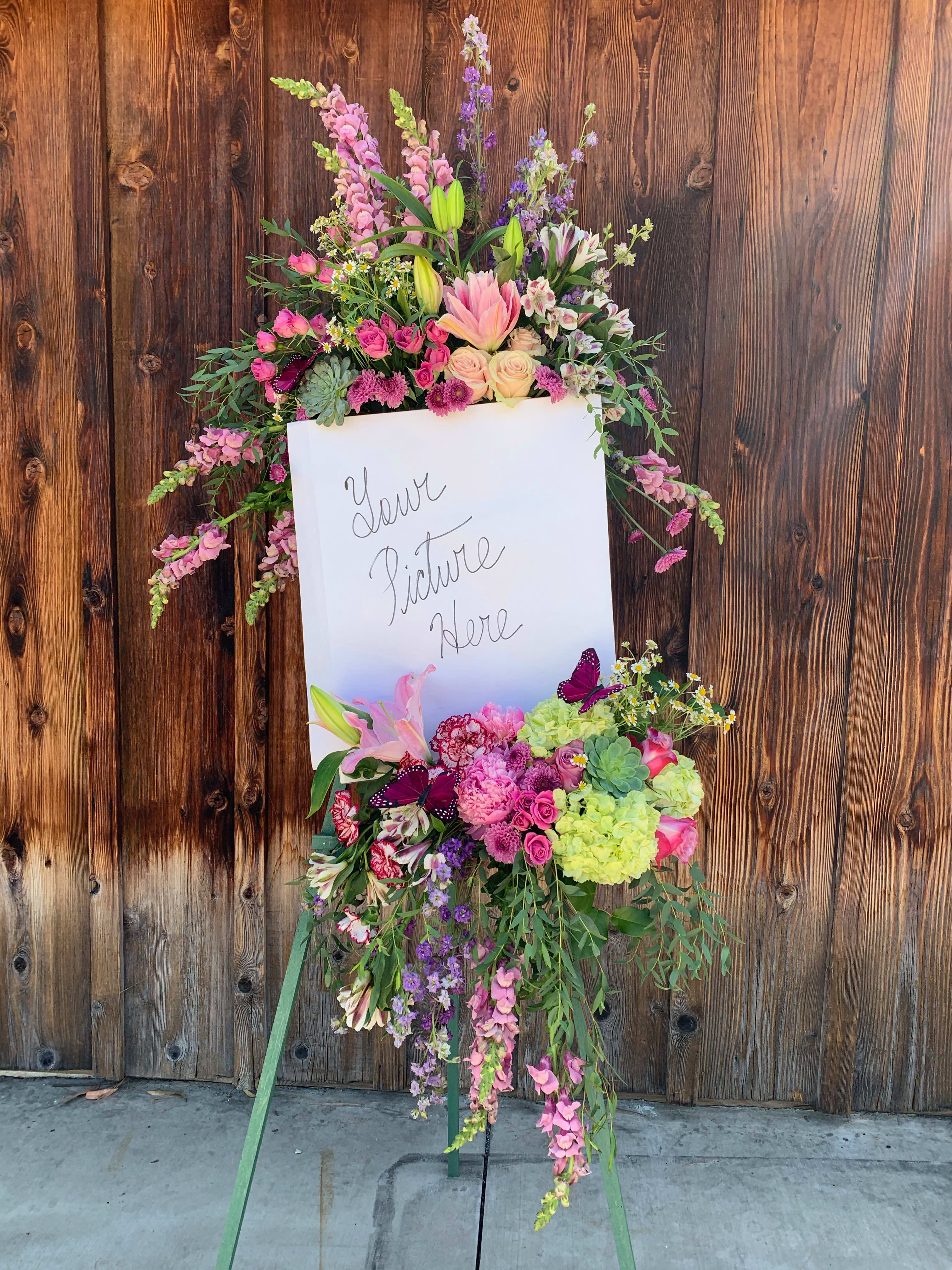 Large standing floral spray with pink, purple, and green blooms on an easel