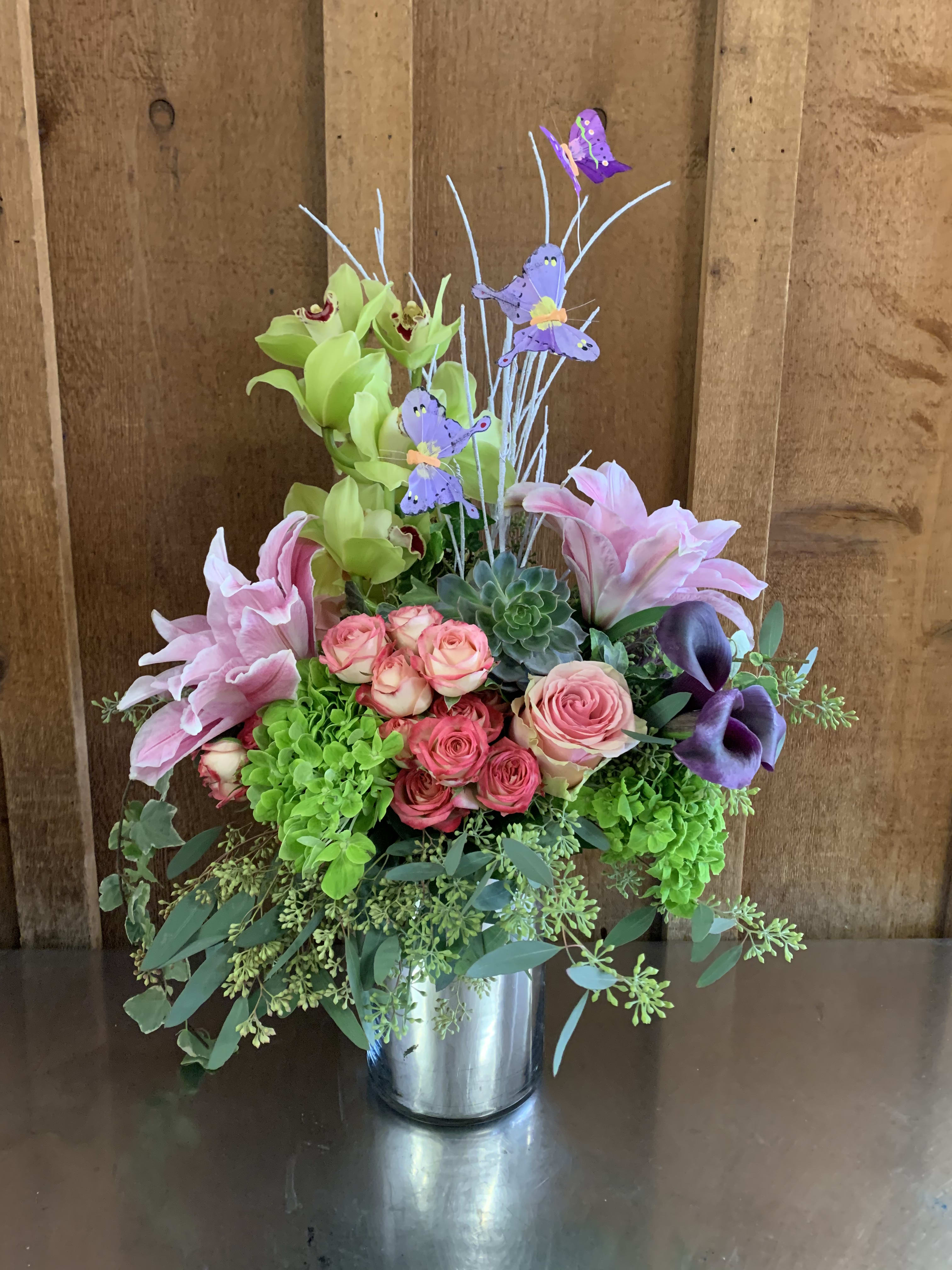 Mixed floral arrangement in a metal vase with pink roses and lilies