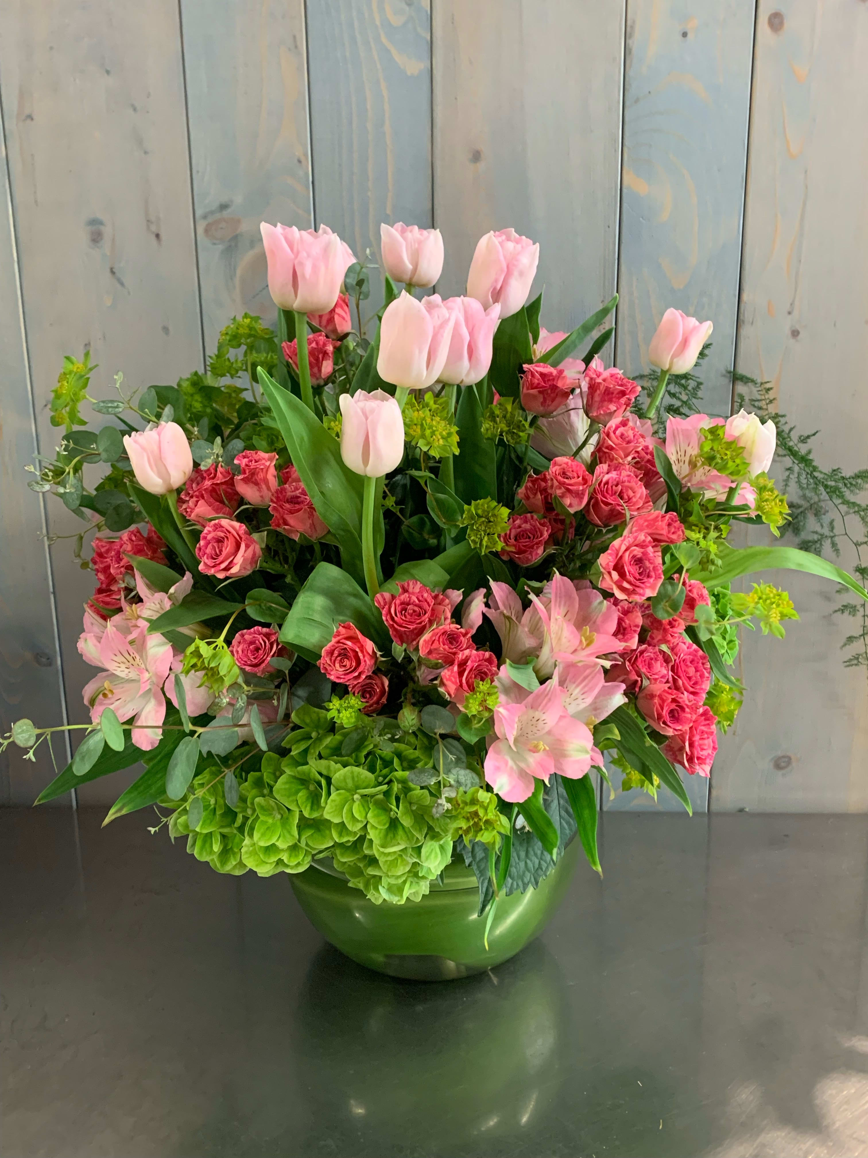 Pink tulips and roses arranged in a green vase