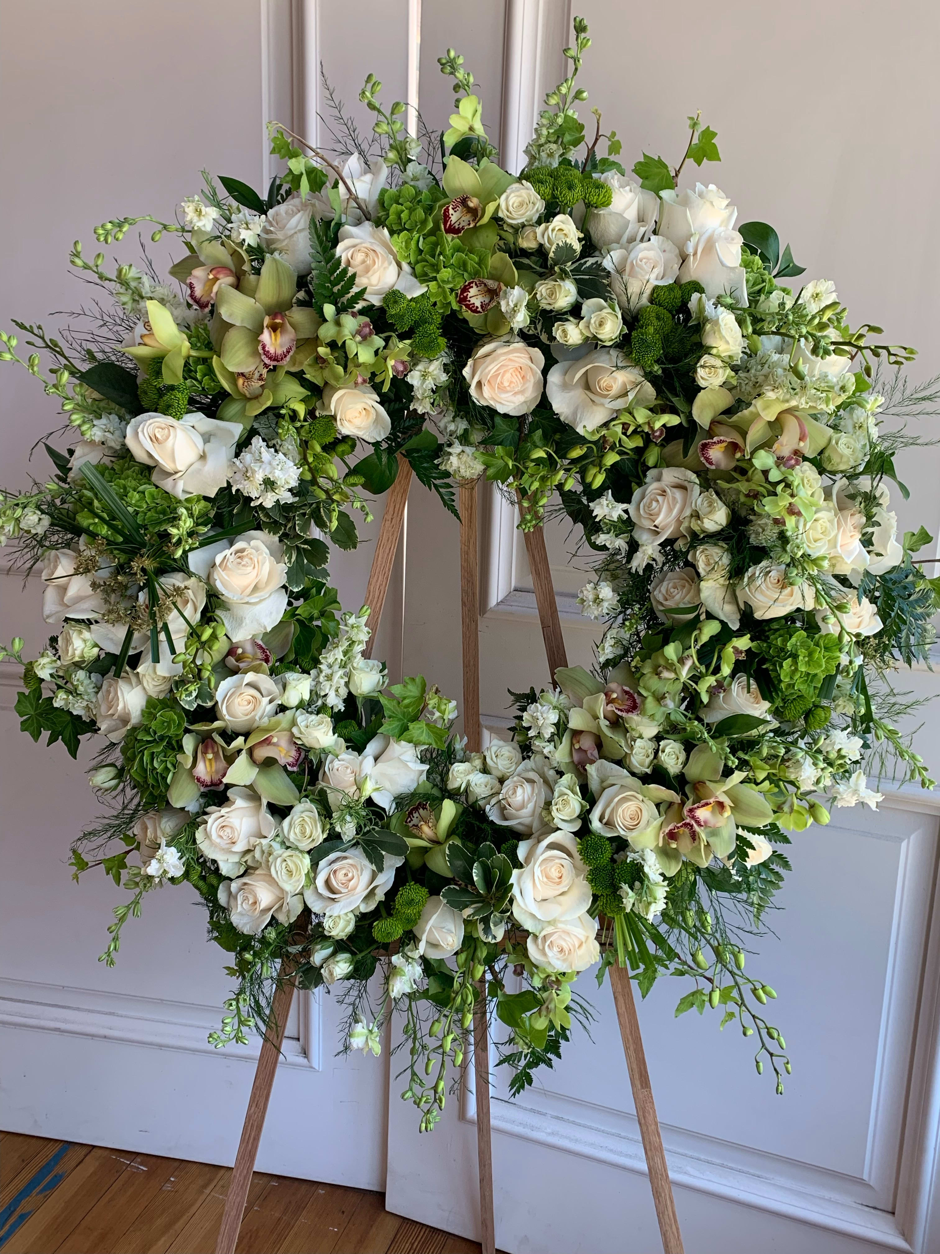 Large floral wreath on a wooden easel with white and green blooms