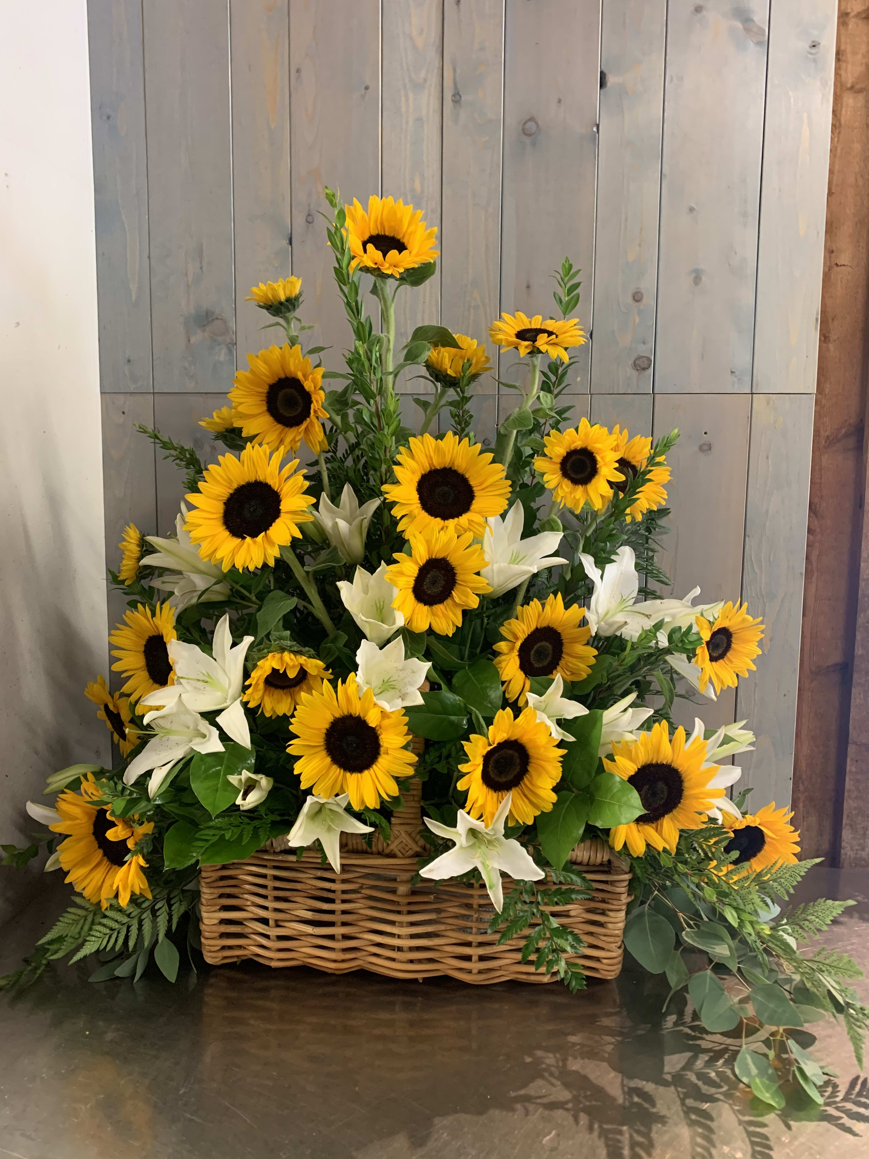 Basket arrangement of sunflowers and white lilies