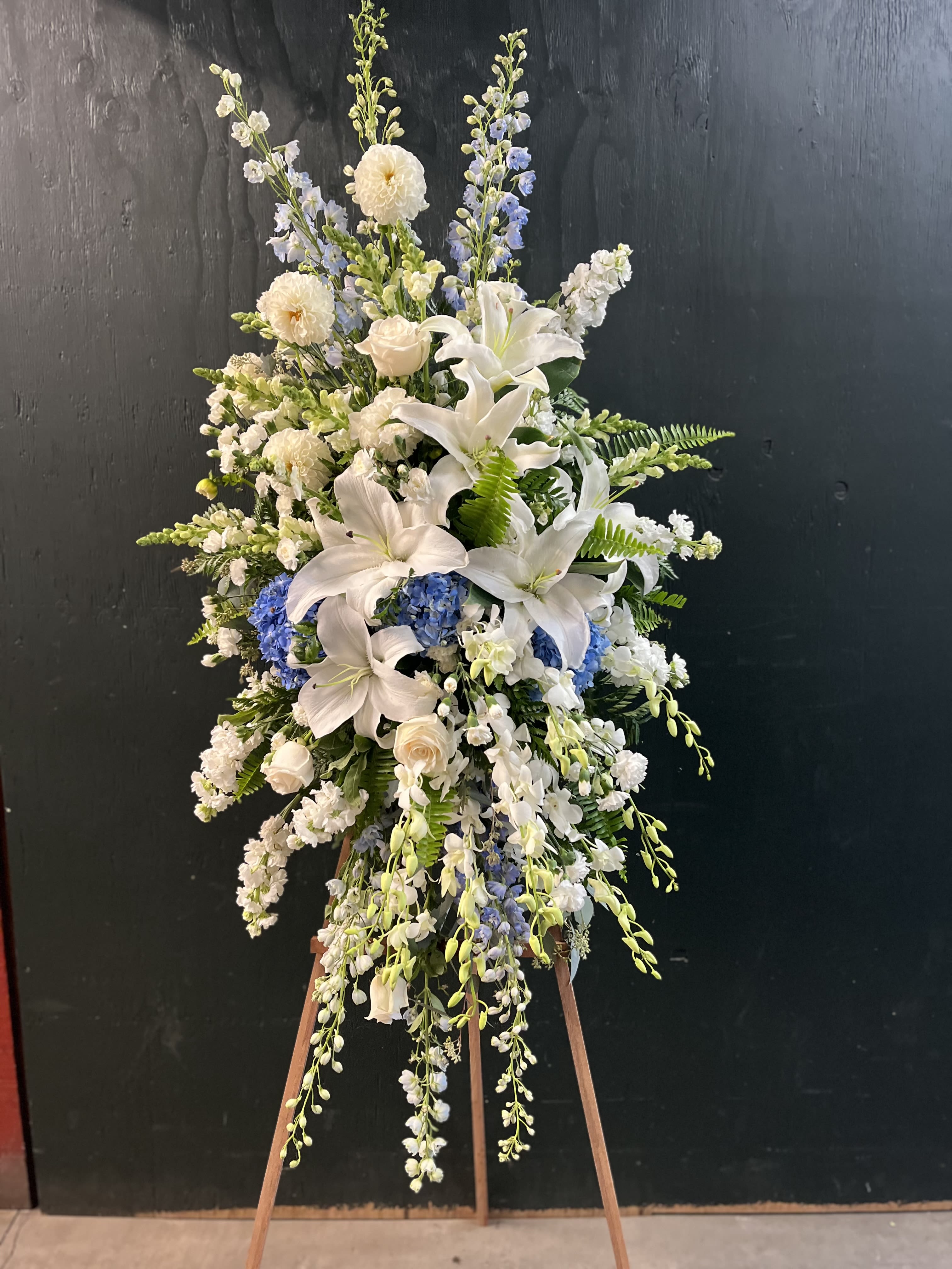 Tall white and blue floral standing spray on an easel
