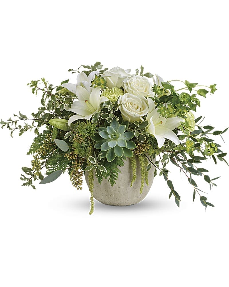 White roses and lilies in a round ceramic vase with trailing greenery