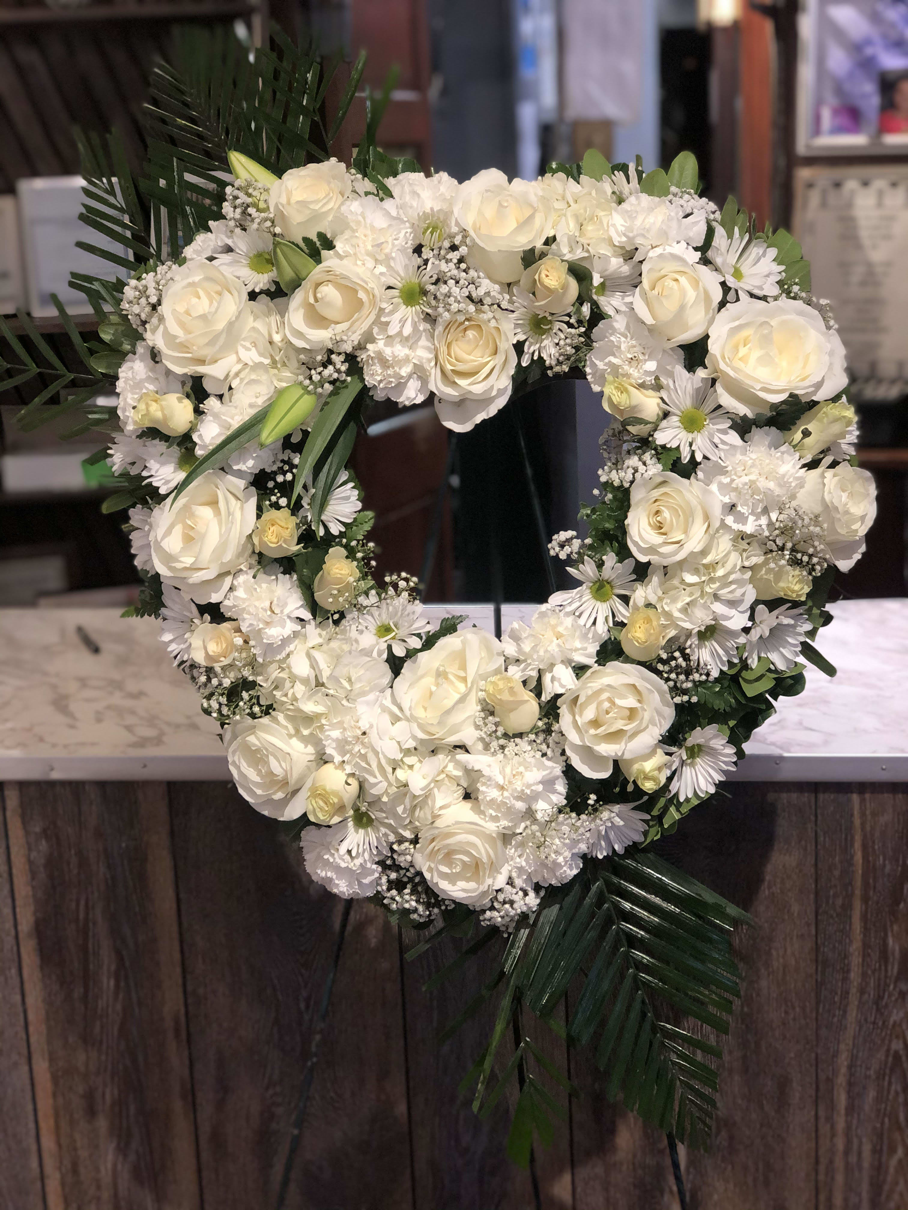 Heart-shaped white floral wreath with roses and daisies