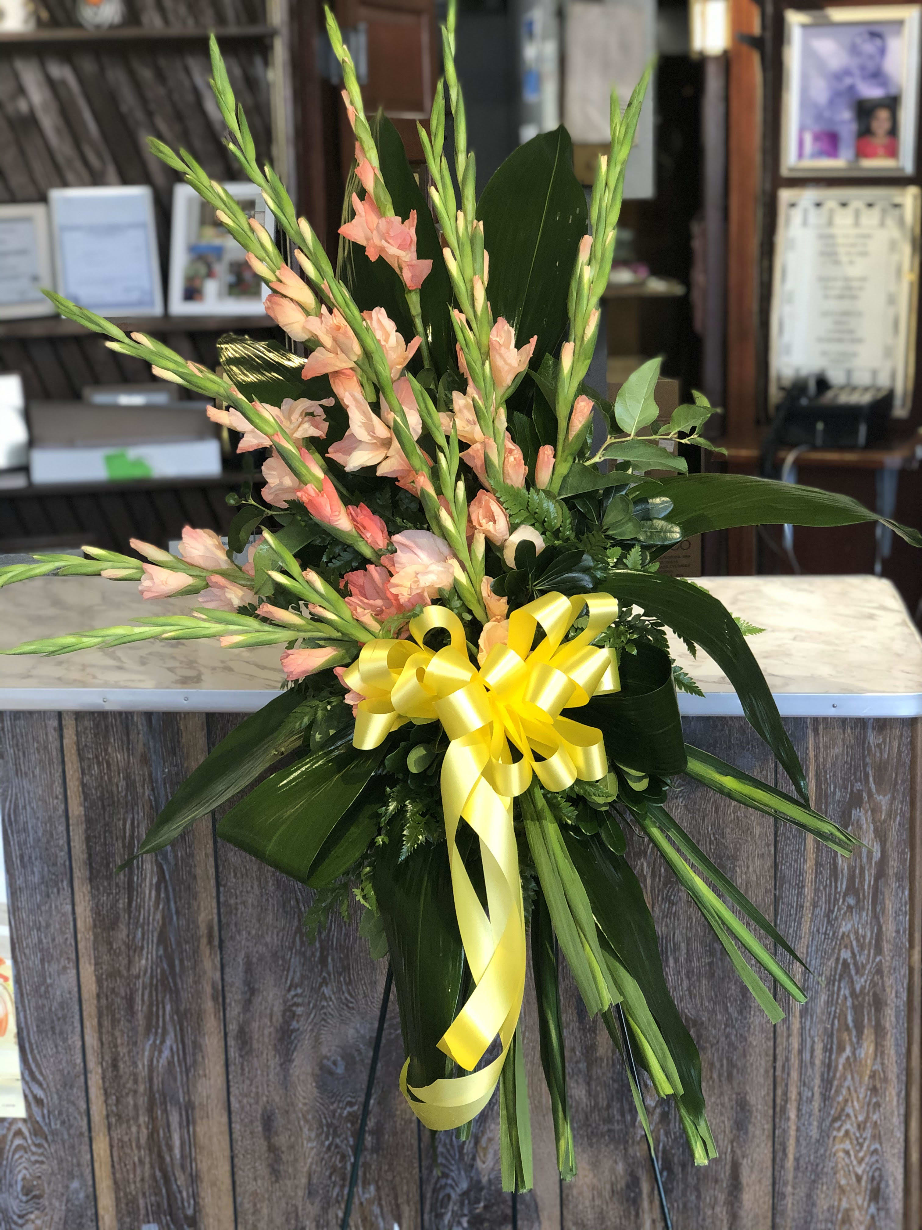 Tall floral spray with peach gladiolus and a yellow ribbon