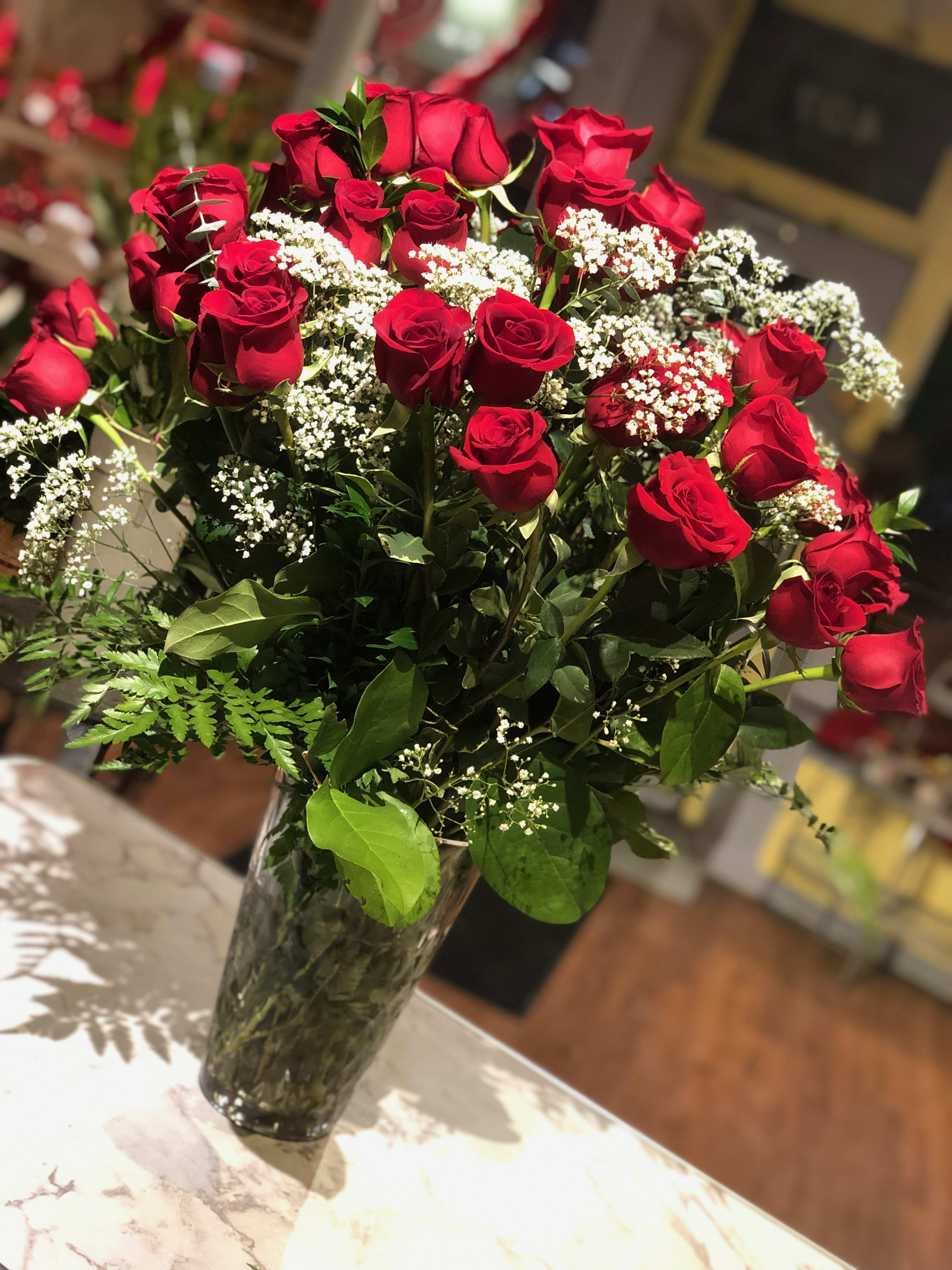 Red roses arranged in a clear glass vase with white baby's breath