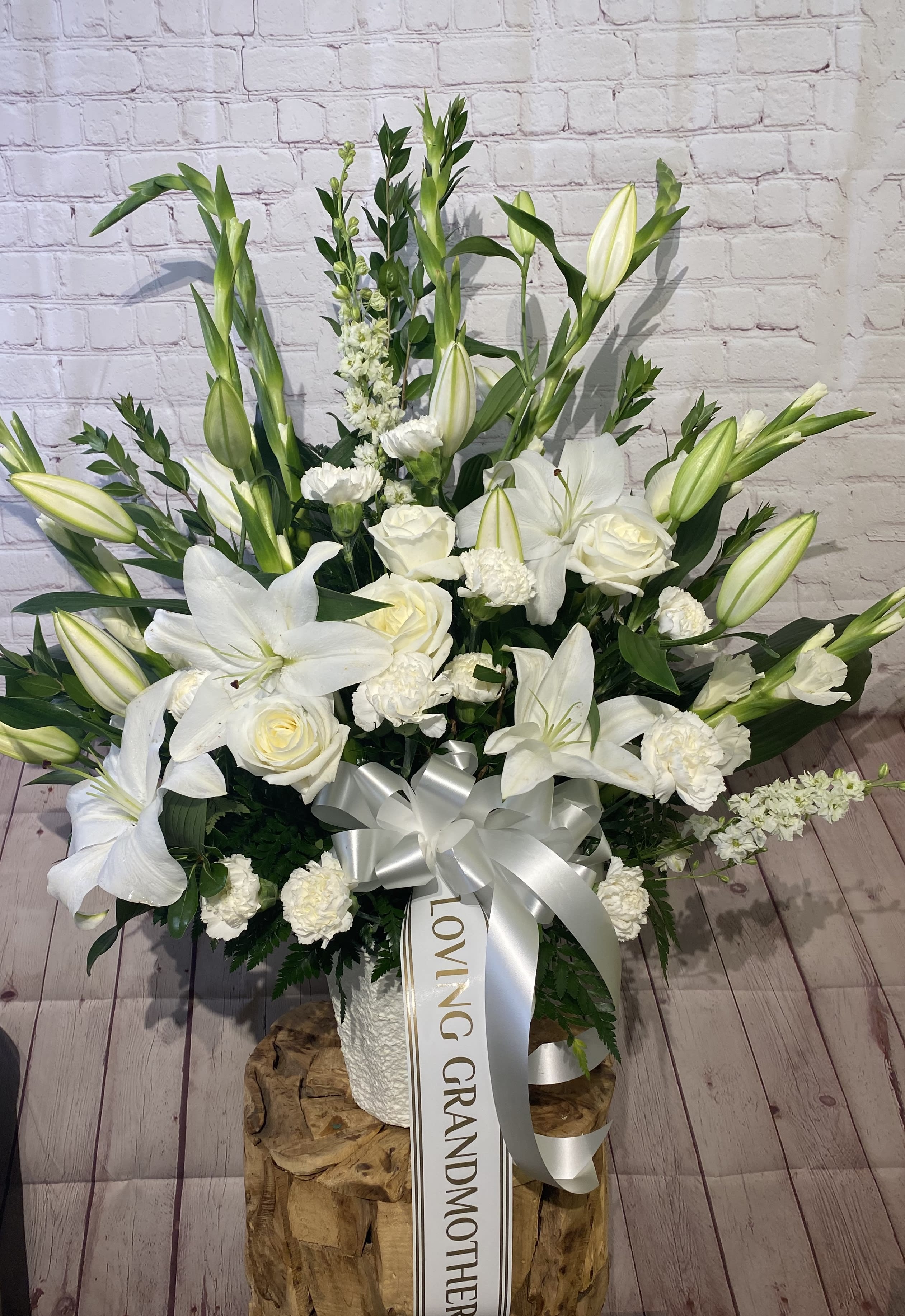 White lilies and roses arranged in a tall bouquet with a silver ribbon