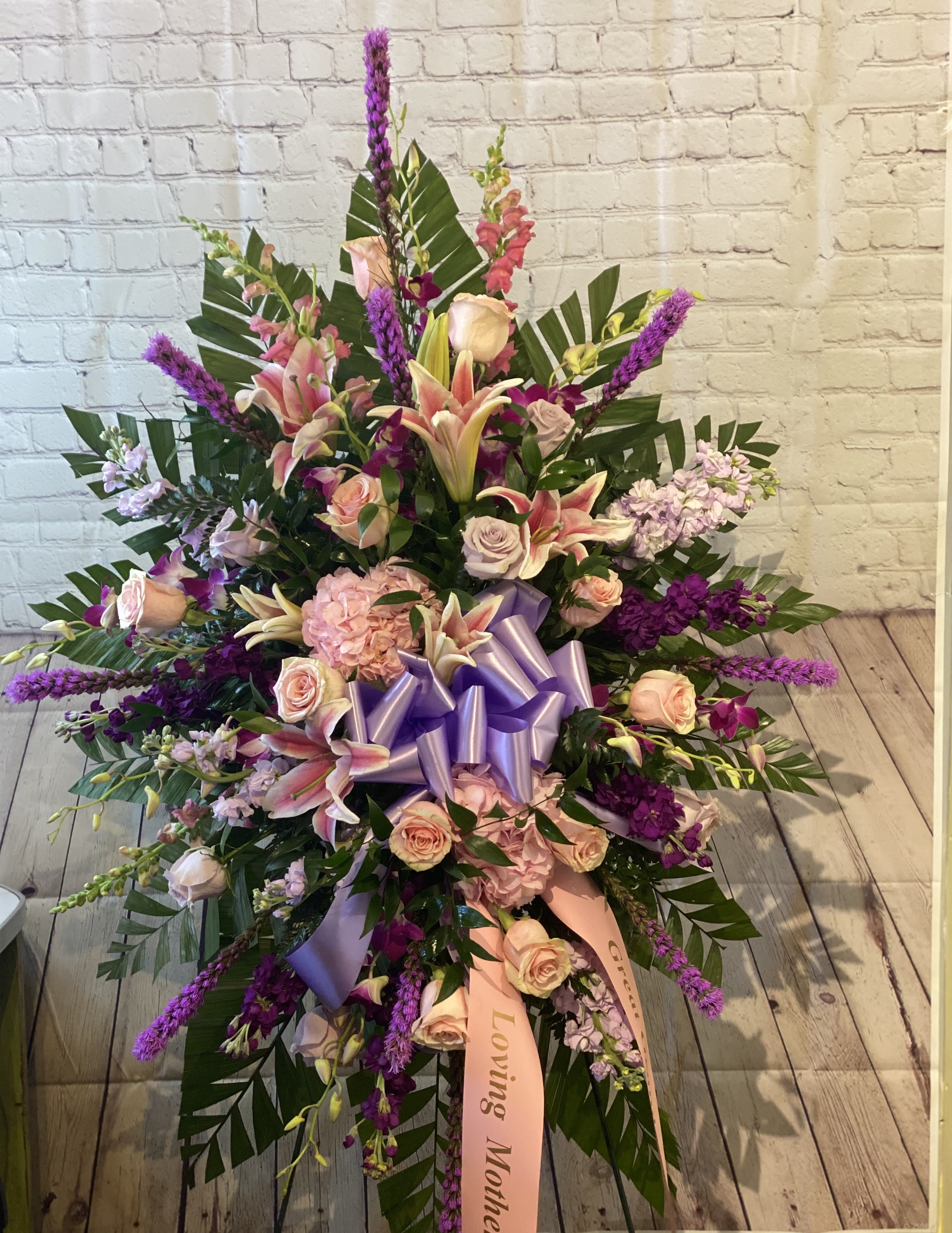 Large standing floral spray with pink lilies, roses, and purple accents