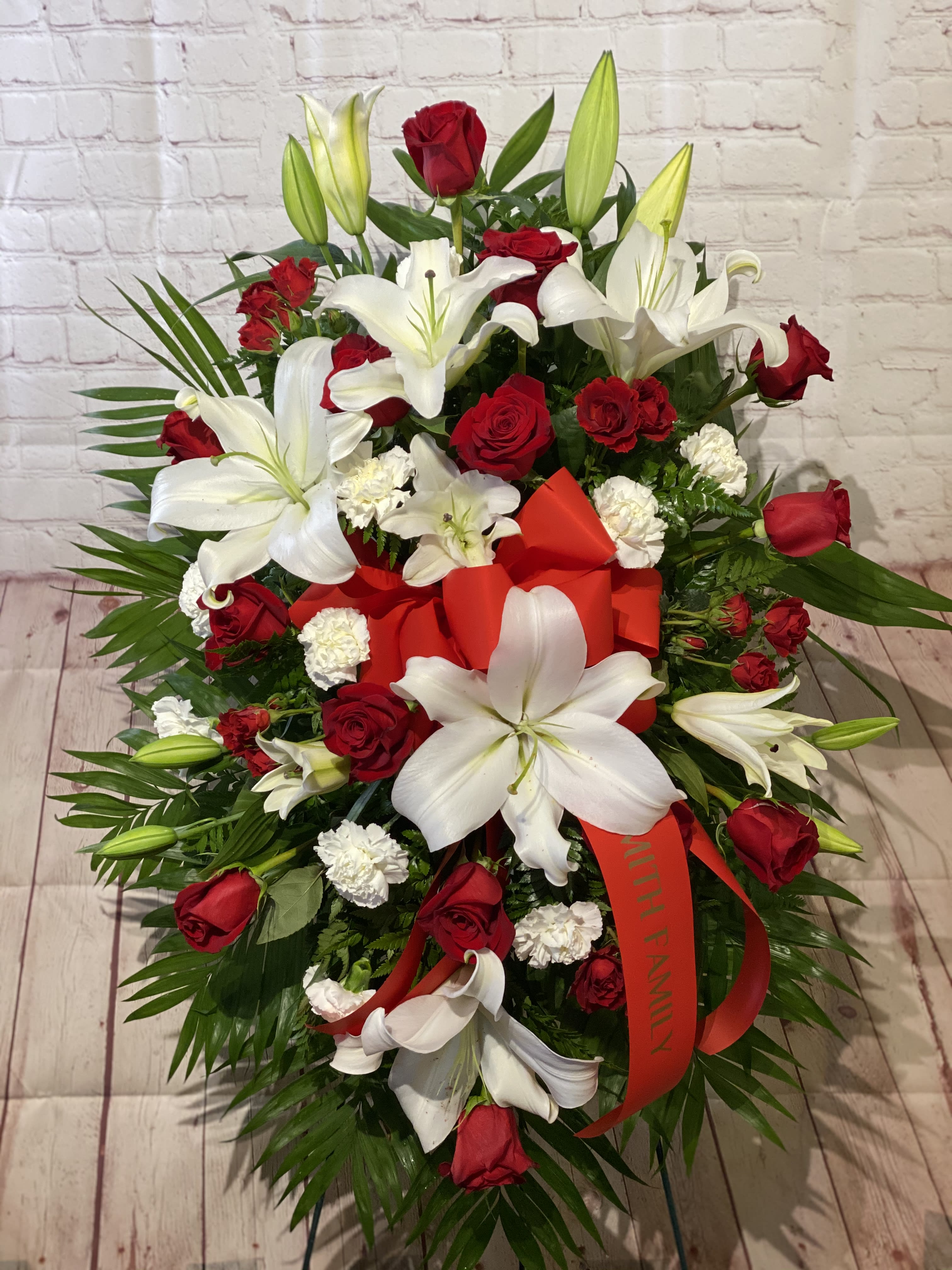 Red roses and white lilies arranged with a red ribbon