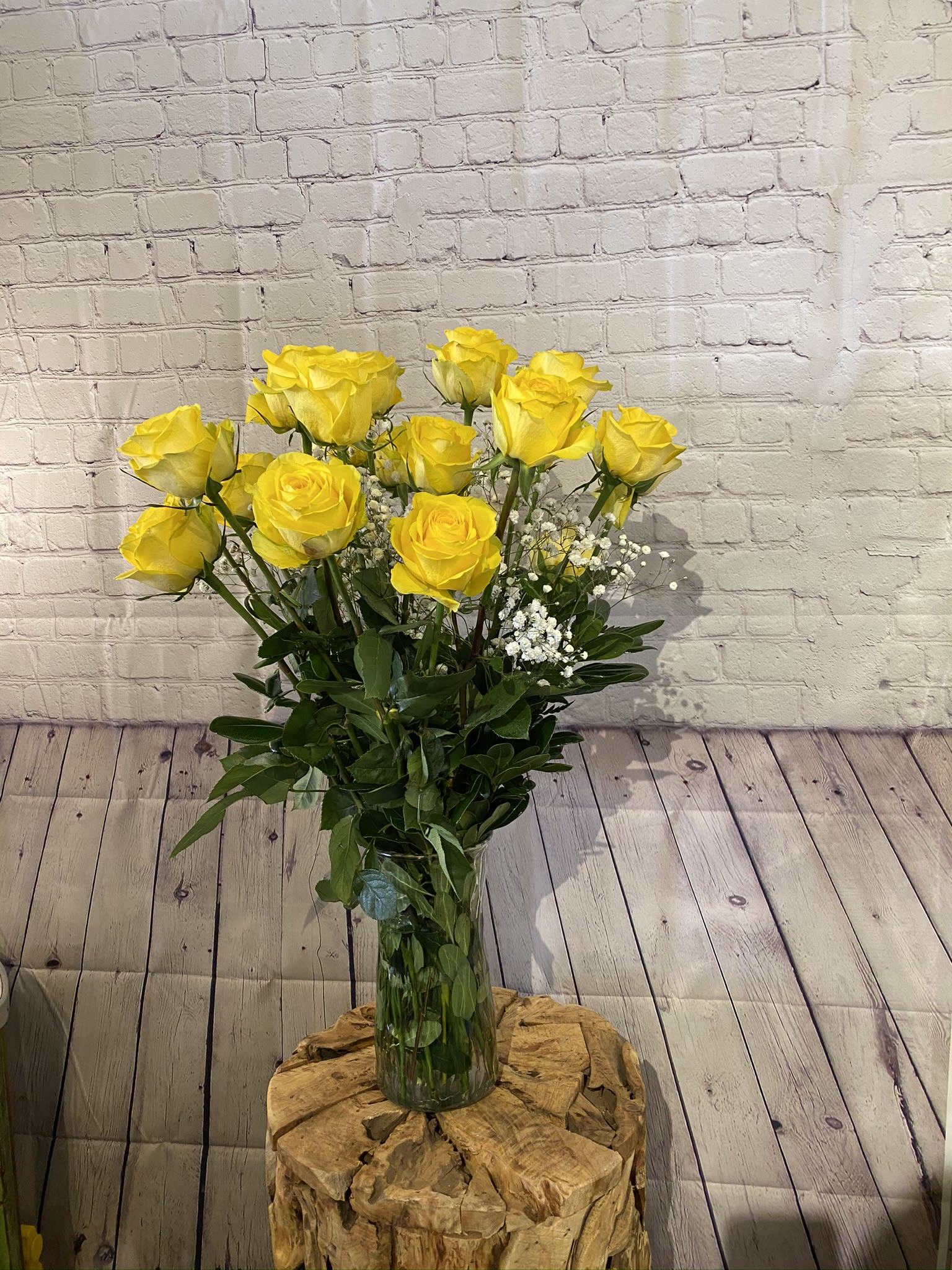 Yellow roses in a clear glass vase with white filler flowers
